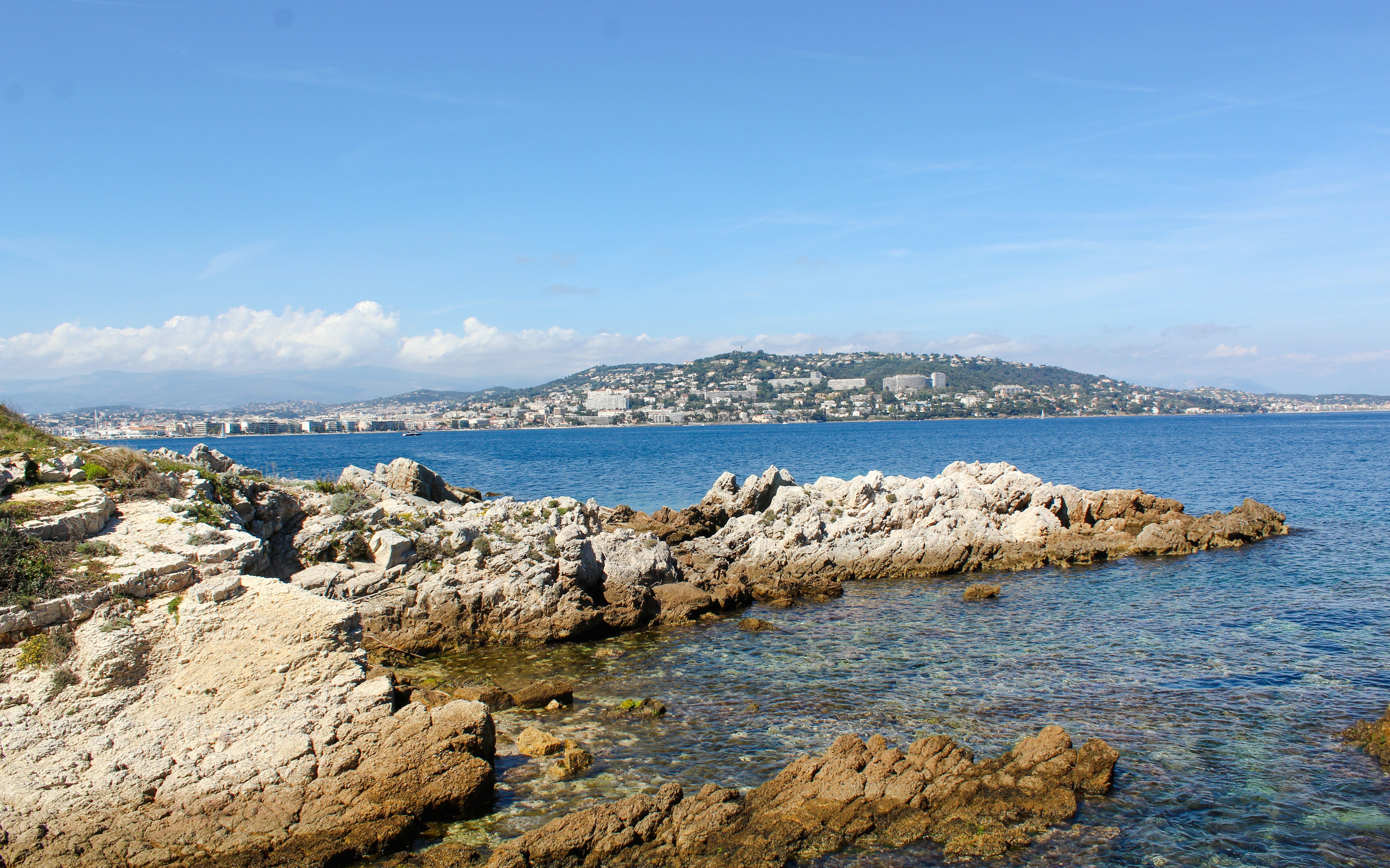 Rocky coastline of Île Sainte-Marguerite with Cannes in the background, France.