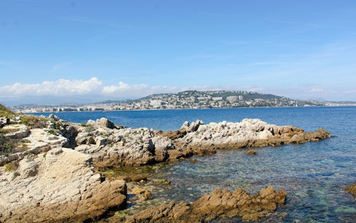 Rocky coastline of Île Sainte-Marguerite with Cannes in the background, France.