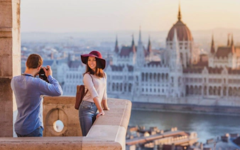 Tourists taking photos with the Hungarian Parliament Building across the Danube River in Budapest.