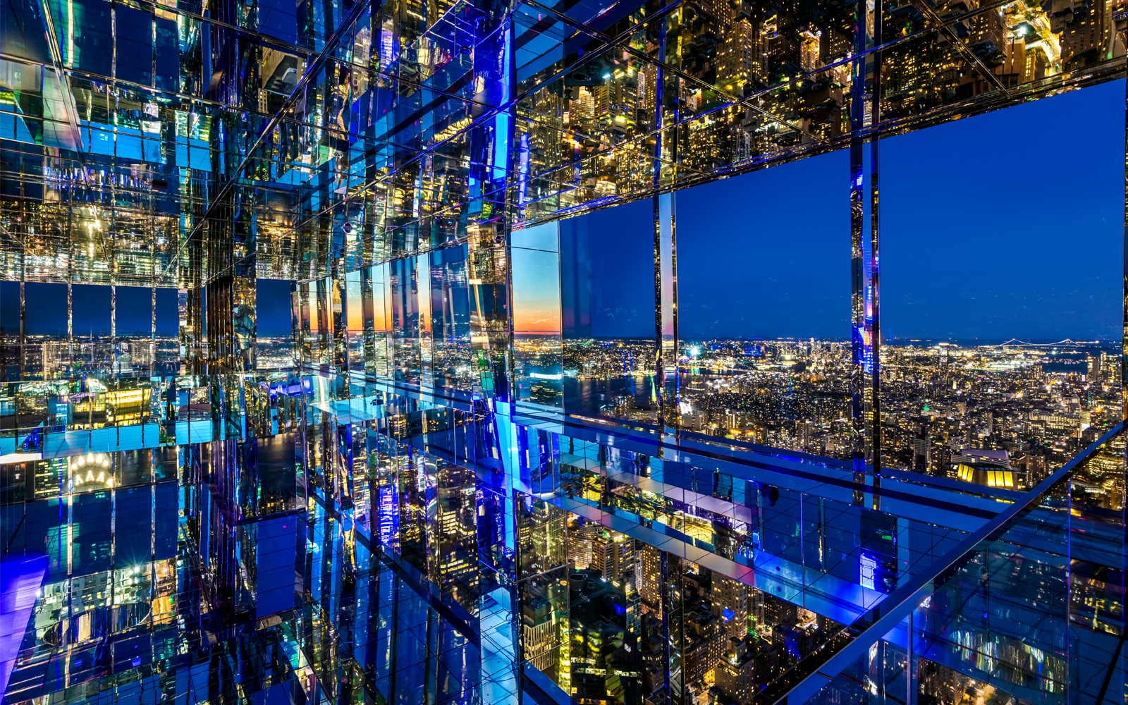 SUMMIT One Vanderbilt mirrored observation deck with New York City skyline at night.
