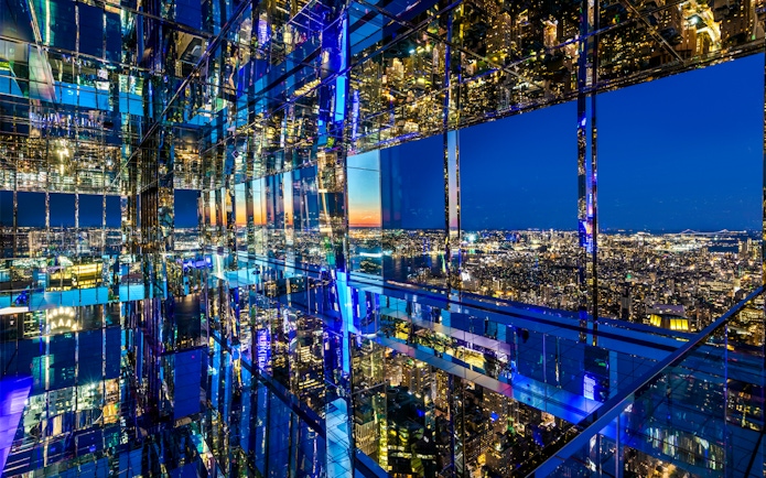 SUMMIT One Vanderbilt mirrored observation deck with New York City skyline at night.