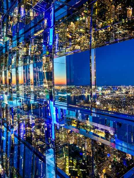 SUMMIT One Vanderbilt mirrored observation deck with New York City skyline at night.