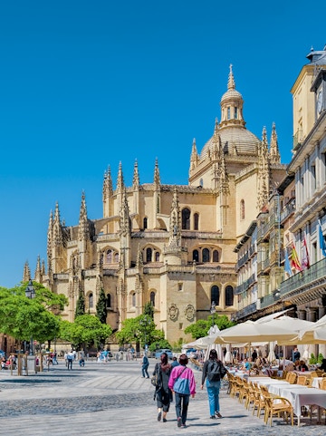 Segovia Cathedral in Plaza Mayor with people walking and outdoor cafes.