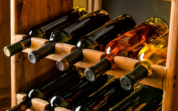 Bottles of wine stored in a wooden cellar rack.