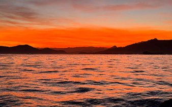 Sunset over the ocean with silhouetted mountains in Arraial do Cabo, Brazil.