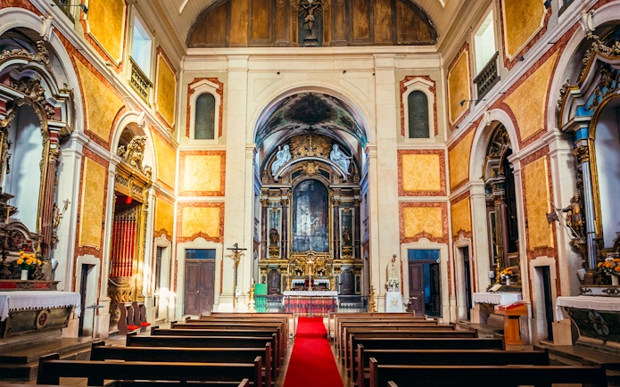 Interior of St George's Castle Church with ornate altar and pews, Lisbon, Portugal.