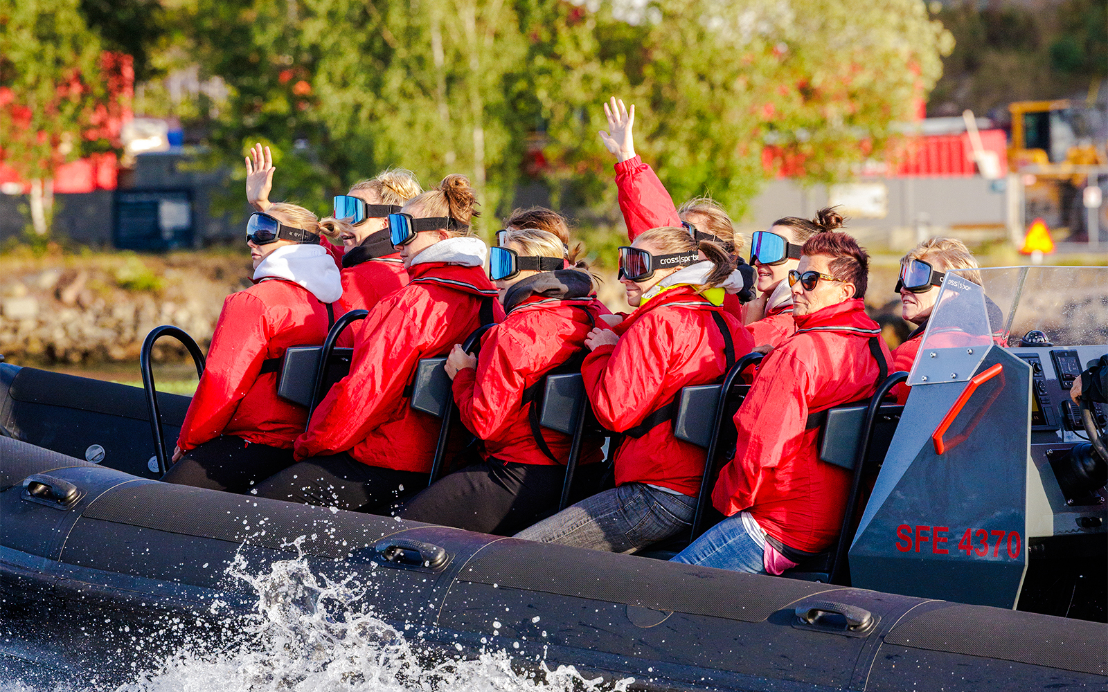 Passengers on a RIB speed boat tour in Stockholm, wearing red jackets and goggles.