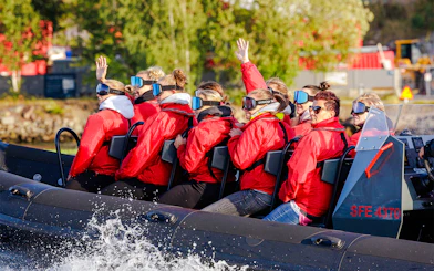 Passengers on a RIB speed boat tour in Stockholm, wearing red jackets and goggles.