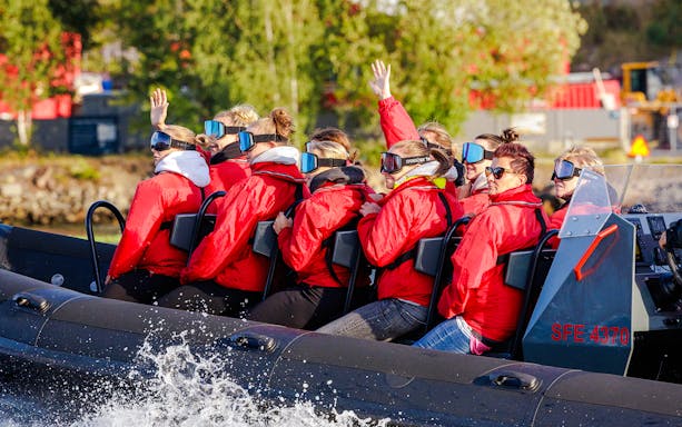Passengers on a RIB speed boat tour in Stockholm, wearing red jackets and goggles.