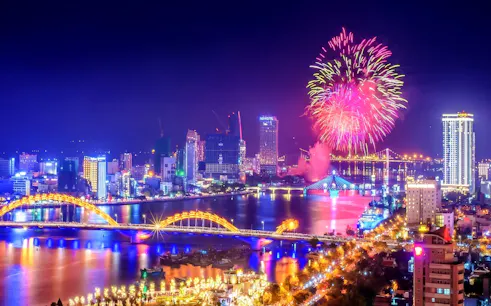 Fireworks over Da Nang skyline with Dragon Bridge and city lights.