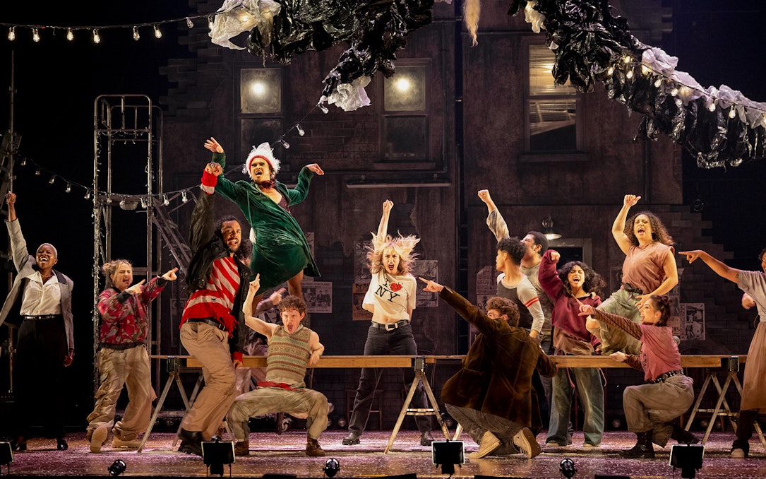 Performers on stage during a lively scene from the musical "Rent" in New York City.