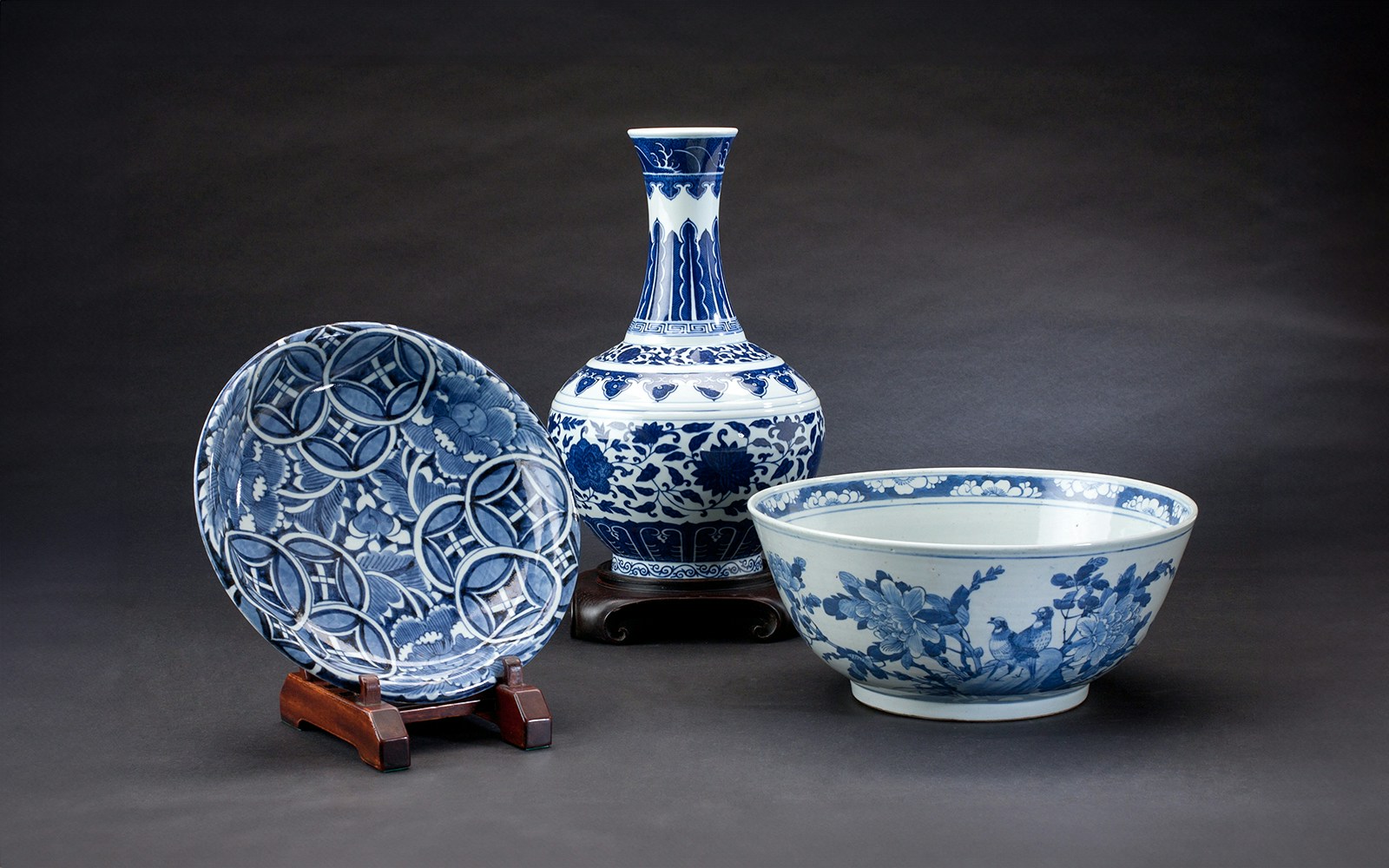 Ancient Chinese porcelain vase, bowl, and plate with blue floral patterns.