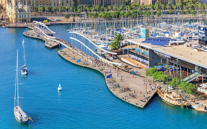 Aerial view of Barcelona's Port Vell with boats and promenade near Montjuic cable car station.