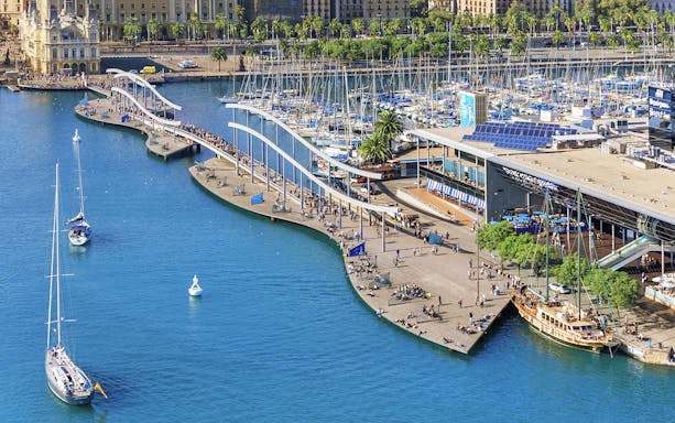 Aerial view of Barcelona's Port Vell with boats and promenade near Montjuic cable car station.