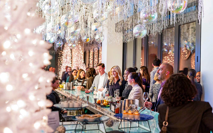 Guests enjoying drinks at the winter-themed bar in View Boston, with festive decorations and lights.