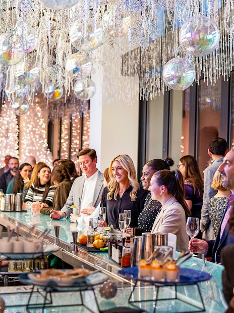 Guests enjoying drinks at the winter-themed bar in View Boston, with festive decorations and lights.