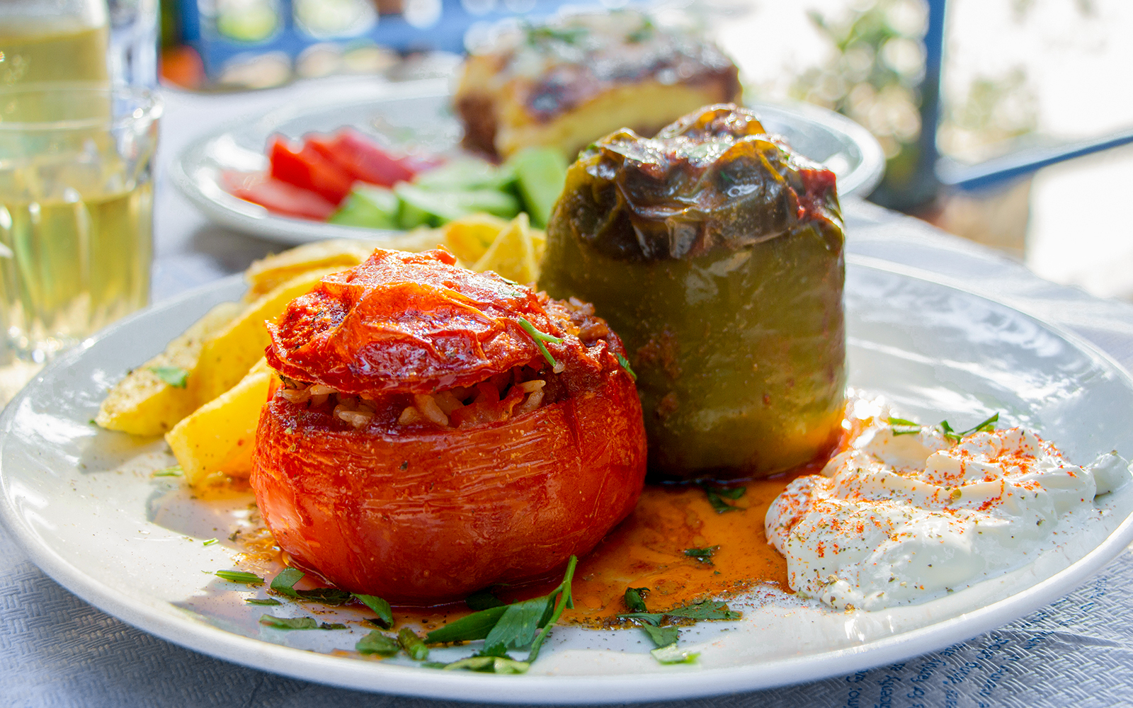Stuffed tomatoes and peppers with rice on a plate, served with retsina in a Greek taverna.