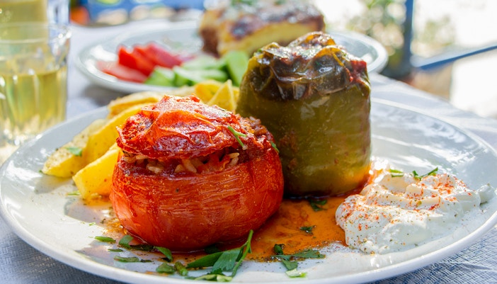 Stuffed tomatoes and peppers with rice on a plate, served with retsina in a Greek taverna.