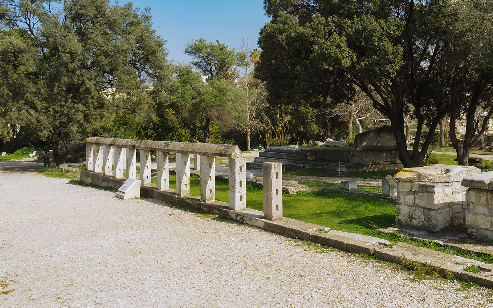 Ancient Agora ruins with stone structures and trees, Athens, Greece.