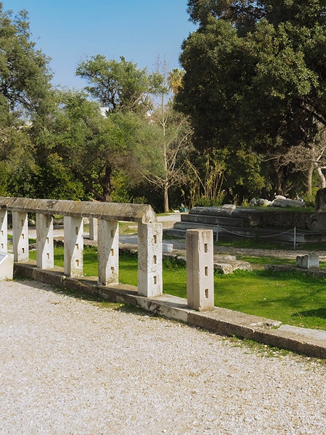 Ancient Agora ruins with stone structures and trees, Athens, Greece.