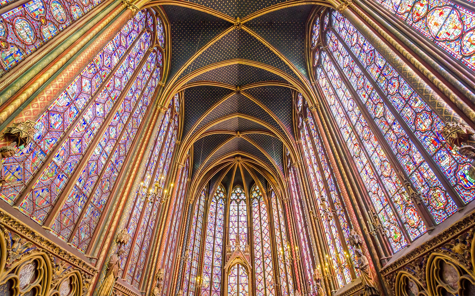 Sainte-Chapelle stained glass windows and vaulted ceiling painted in blue with golden motifs, Paris.