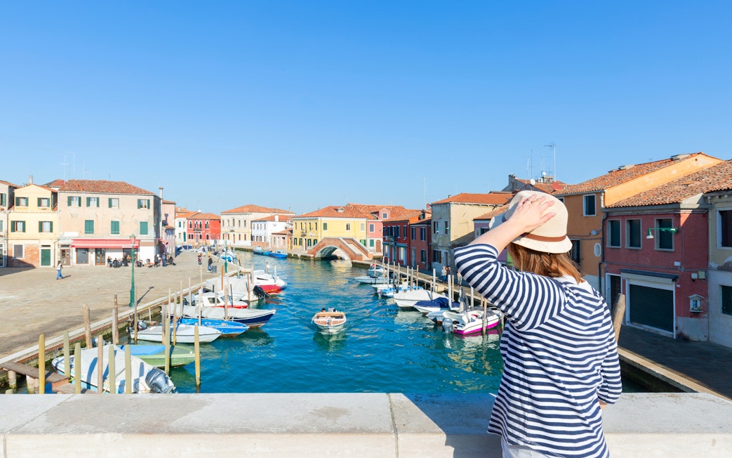 Traveler viewing colorful buildings and canal on Murano Island, near Venice, Italy.