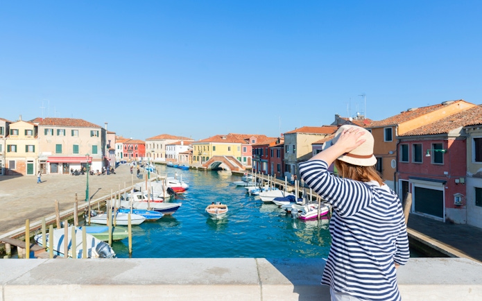 Traveler viewing colorful buildings and canal on Murano Island, near Venice, Italy.