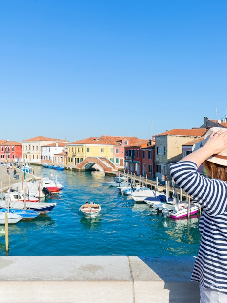 Traveler viewing colorful buildings and canal on Murano Island, near Venice, Italy.