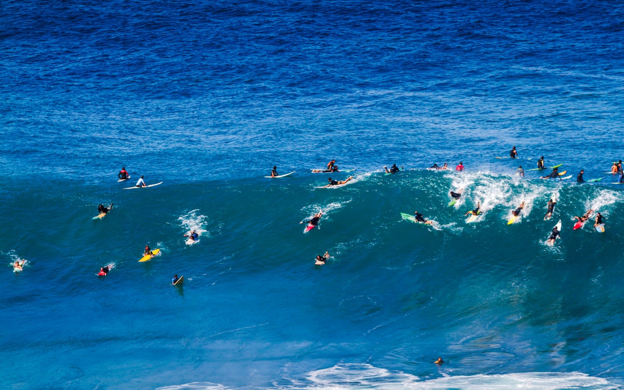 Surfers riding waves at Waimea Bay on Oahu's North Shore, Hawaii.