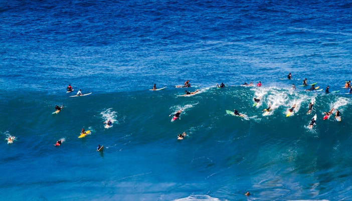 Surfers riding waves at Waimea Bay on Oahu's North Shore, Hawaii.
