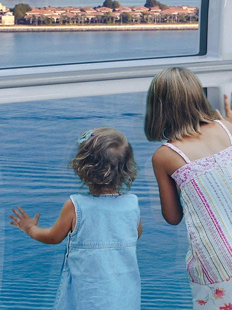 Children looking out from Ain Dubai wheel at waterfront view.