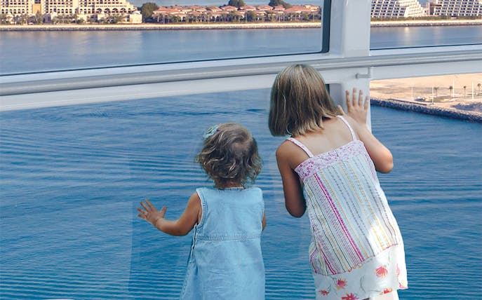 Children looking out from Ain Dubai wheel at waterfront view.