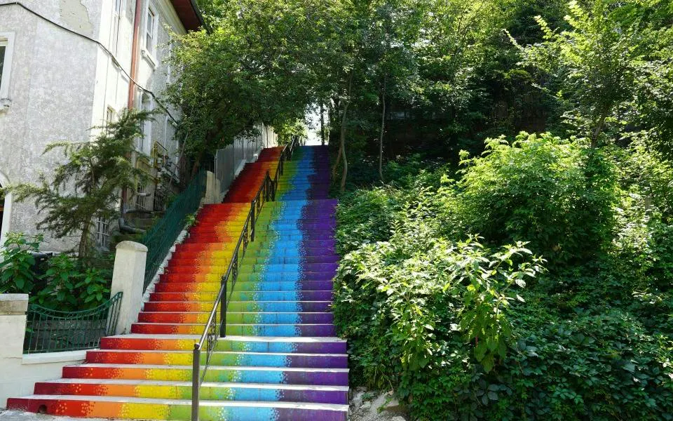 Rainbow-painted stairs surrounded by greenery in Cotroceni, Bucharest.