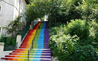 Rainbow-painted stairs surrounded by greenery in Cotroceni, Bucharest.