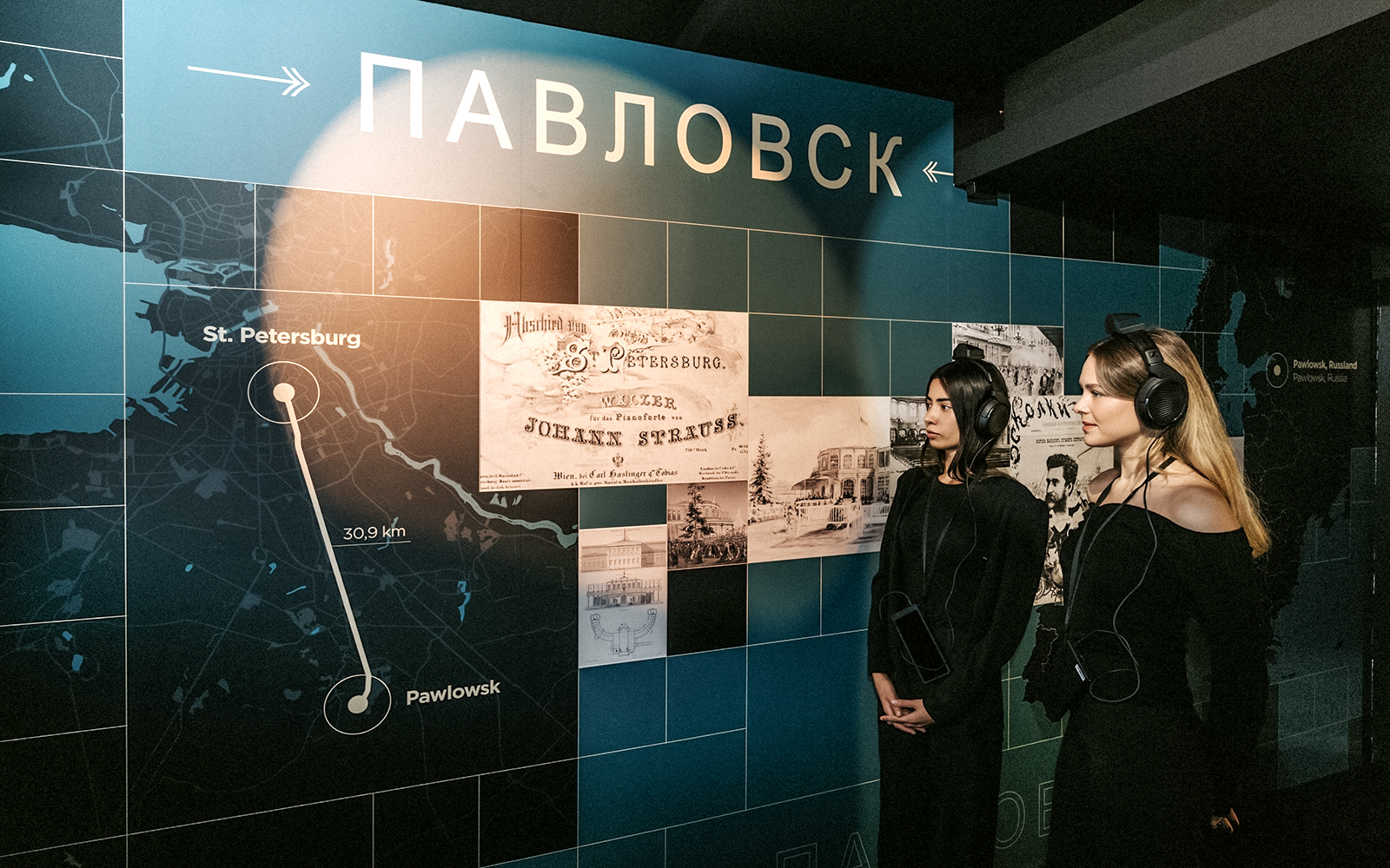 Visitors listening to audio guide at Vienna's Johann Strauss Museum exhibit.
