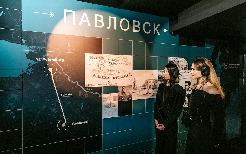 Visitors listening to audio guide at Vienna's Johann Strauss Museum exhibit.