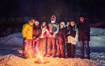 Group gathered around a campfire during a northern lights tour in Kiruna.