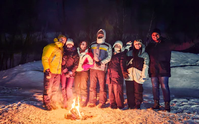 Group gathered around a campfire during a northern lights tour in Kiruna.