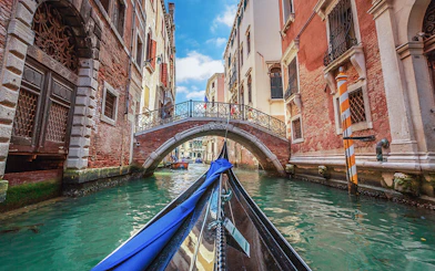 Gondola gliding under a stone bridge in Venice canal.