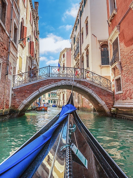 Gondola gliding under a stone bridge in Venice canal.