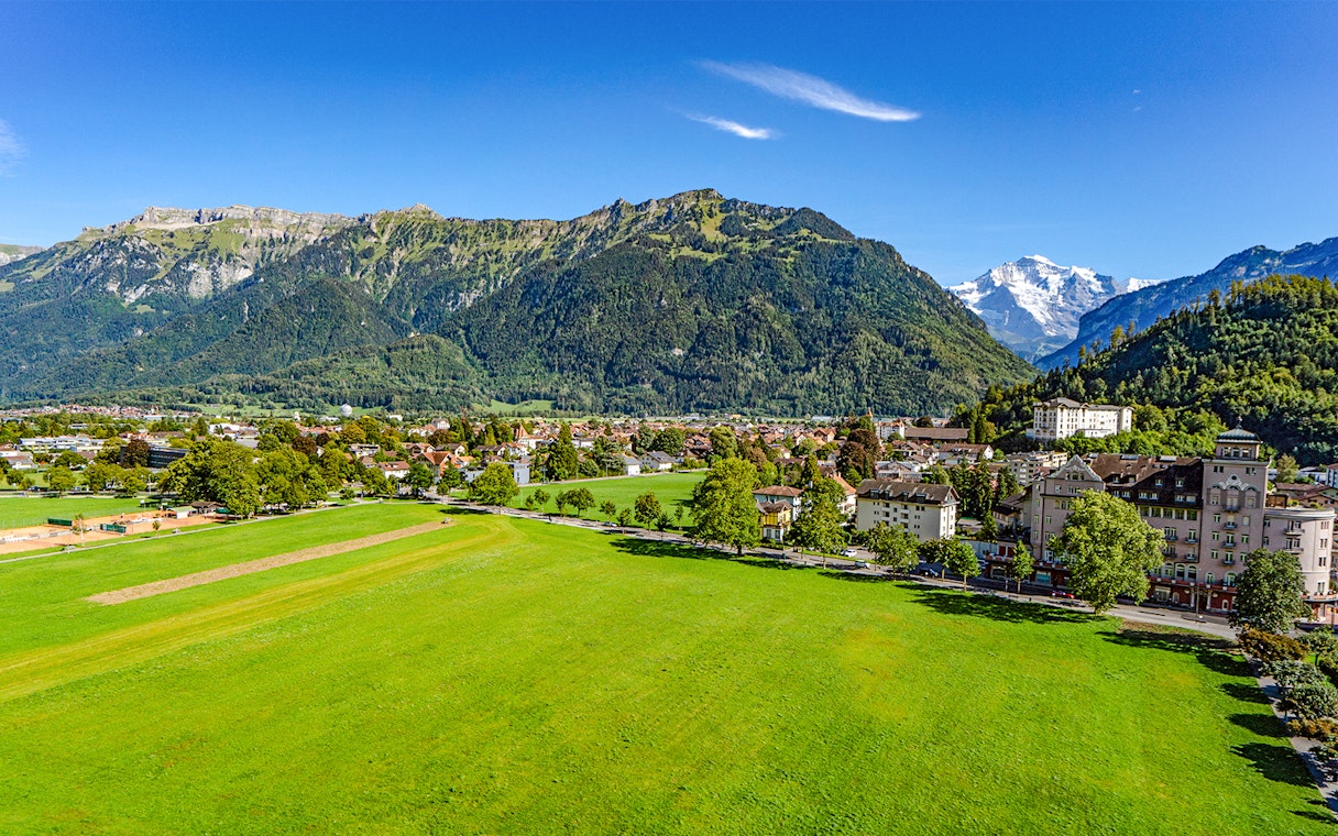 Aerial view of Matten bei Interlaken with lush green fields and mountain backdrop.