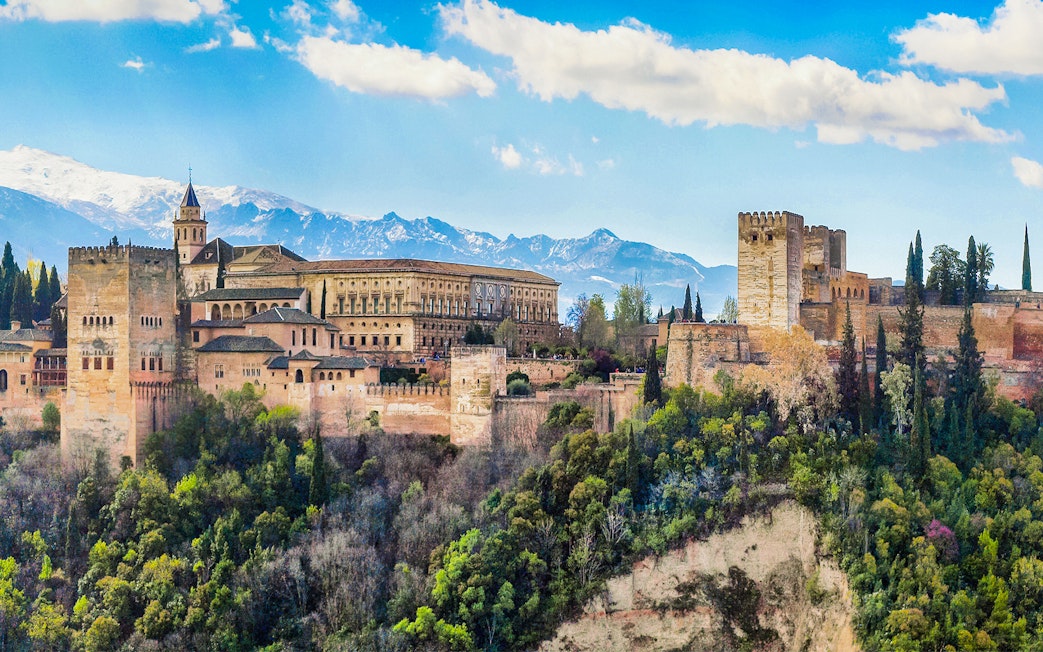 Alhambra fortress in Granada, Spain, with scenic mountain backdrop.