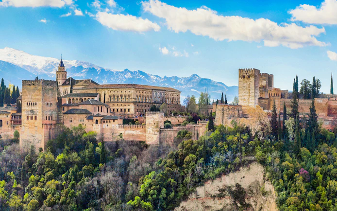 Alhambra fortress in Granada, Spain, with scenic mountain backdrop.