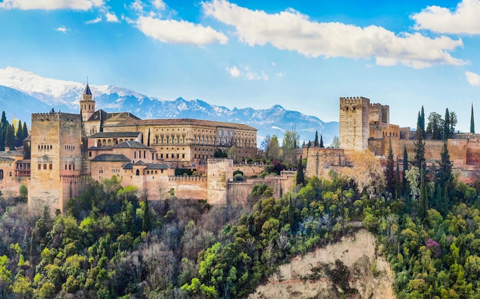 Alhambra fortress in Granada, Spain, with scenic mountain backdrop.