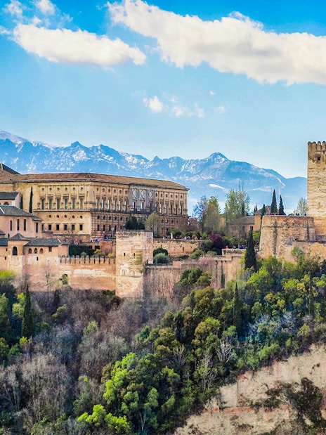 Alhambra fortress in Granada, Spain, with scenic mountain backdrop.