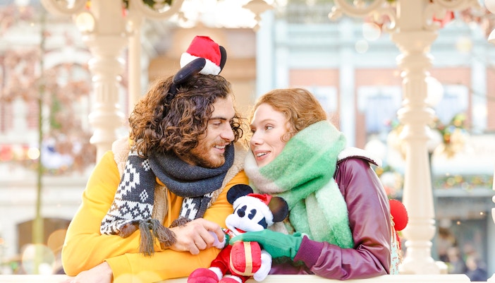Couple enjoying Disneyland Christmas 2025 with Mickey Mouse plush.
