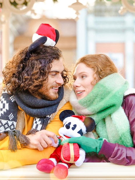 Couple enjoying Disneyland Christmas 2025 with Mickey Mouse plush.