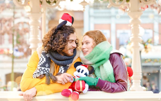 Couple enjoying Disneyland Christmas 2025 with Mickey Mouse plush.