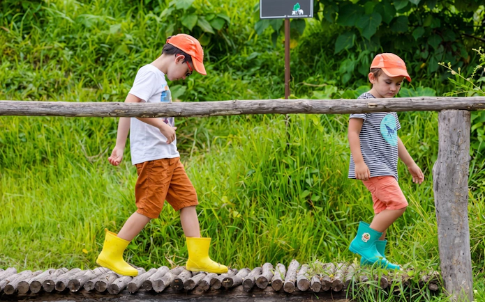 Children crossing a wooden log bridge at Phuket Elephant Nature Park viewpoint.