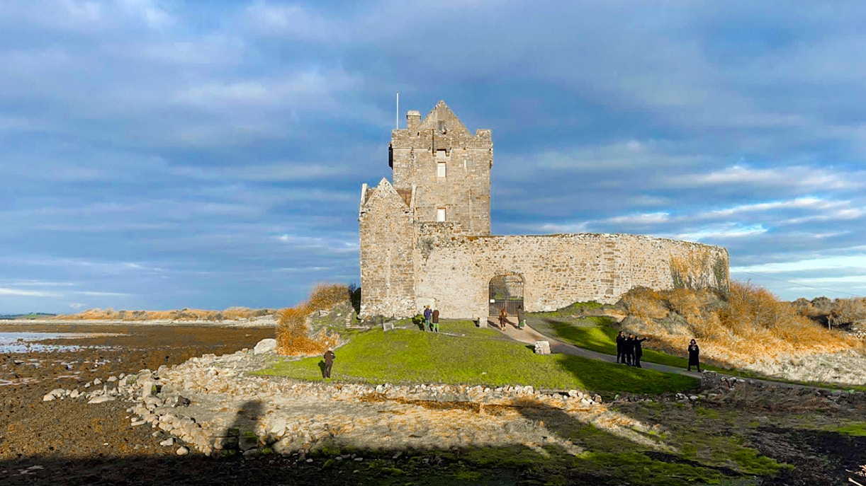 Dunguaire Castle in Ireland with visitors exploring the grounds.